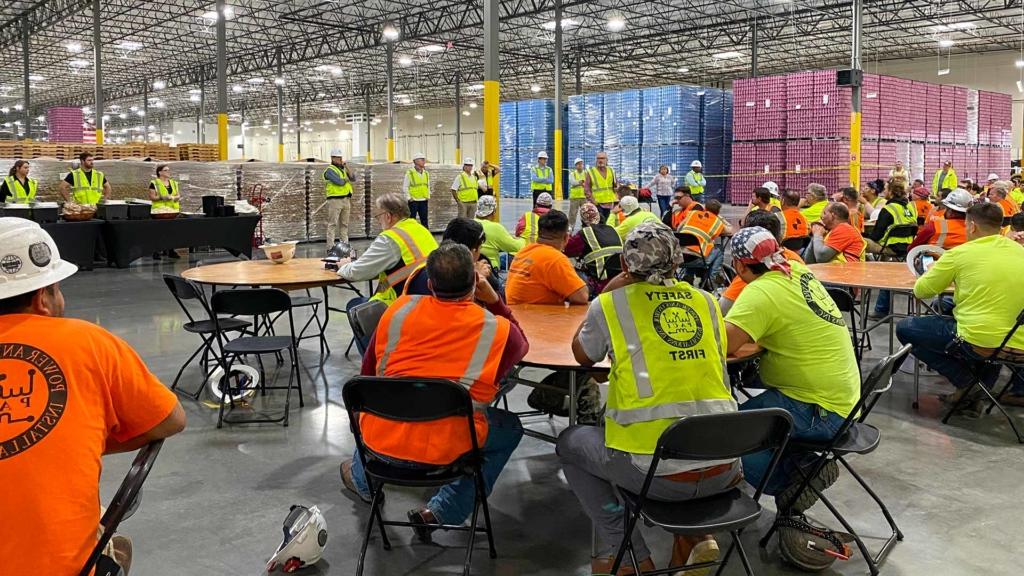 A 澳门足彩app construction crew gathers for a meeting in Bang Energy's giant warehouse